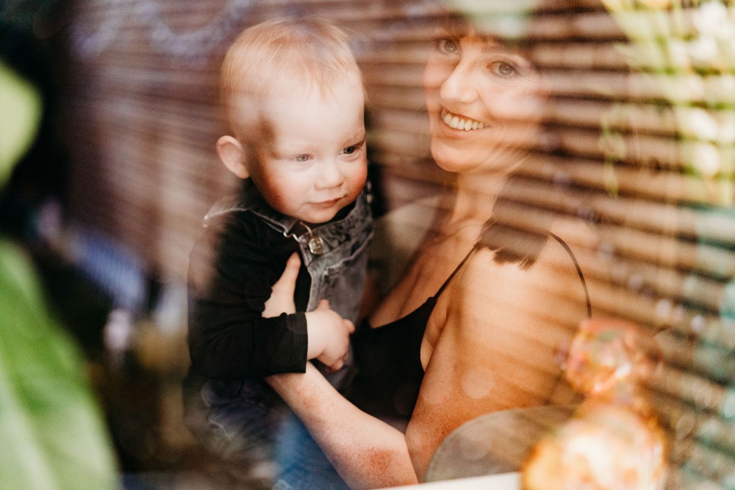 Dreamy window reflection capturing intimate family moment with soft lighting effects.  Family PHOTOGRAPHER Dublin