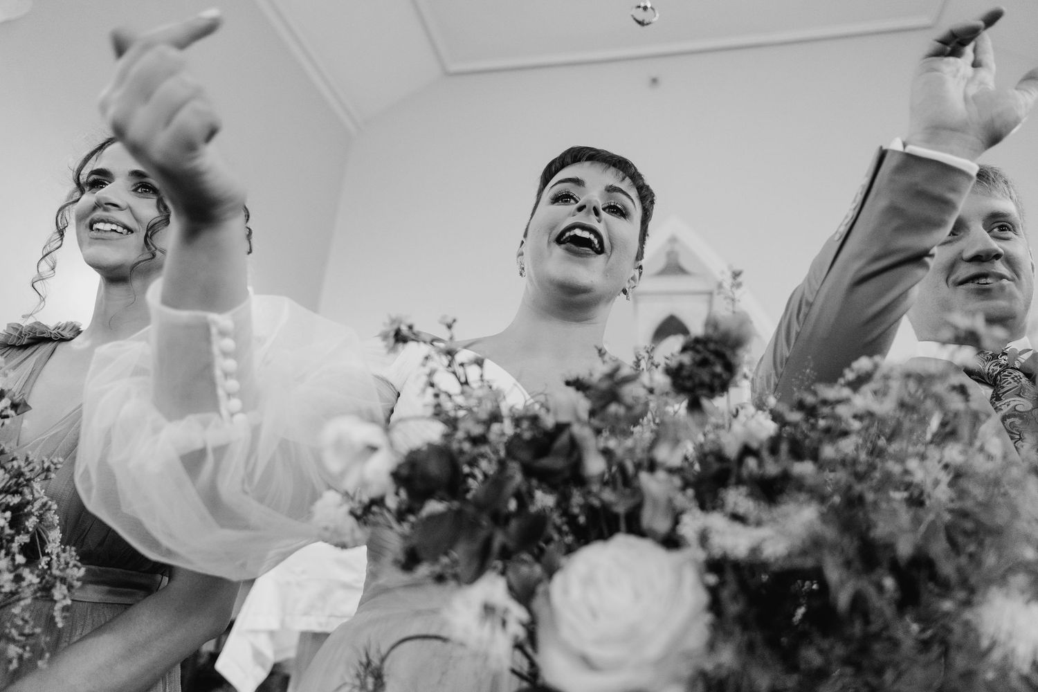 A joyful black and white wedding reception photo capturing celebratory emotions with floral arrangements visible.Millhouse slane wedding pho