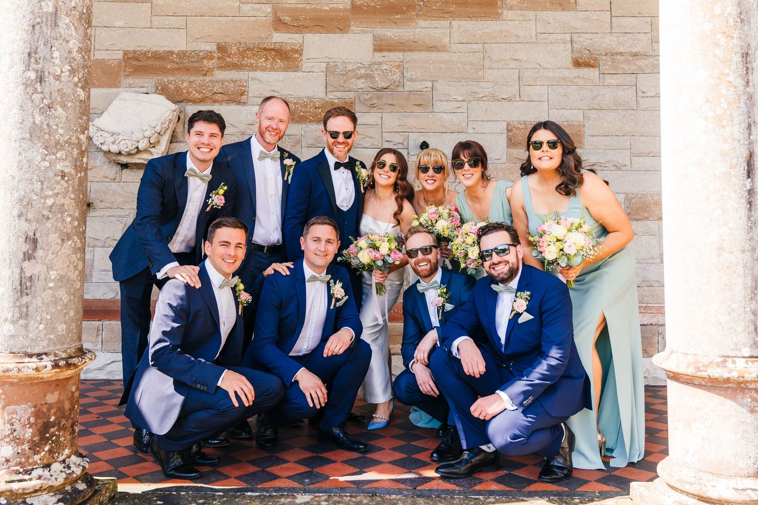 Castle Leslie Wedding Photographer Dublin Wedding party in coordinated navy attire posing together in an archway.