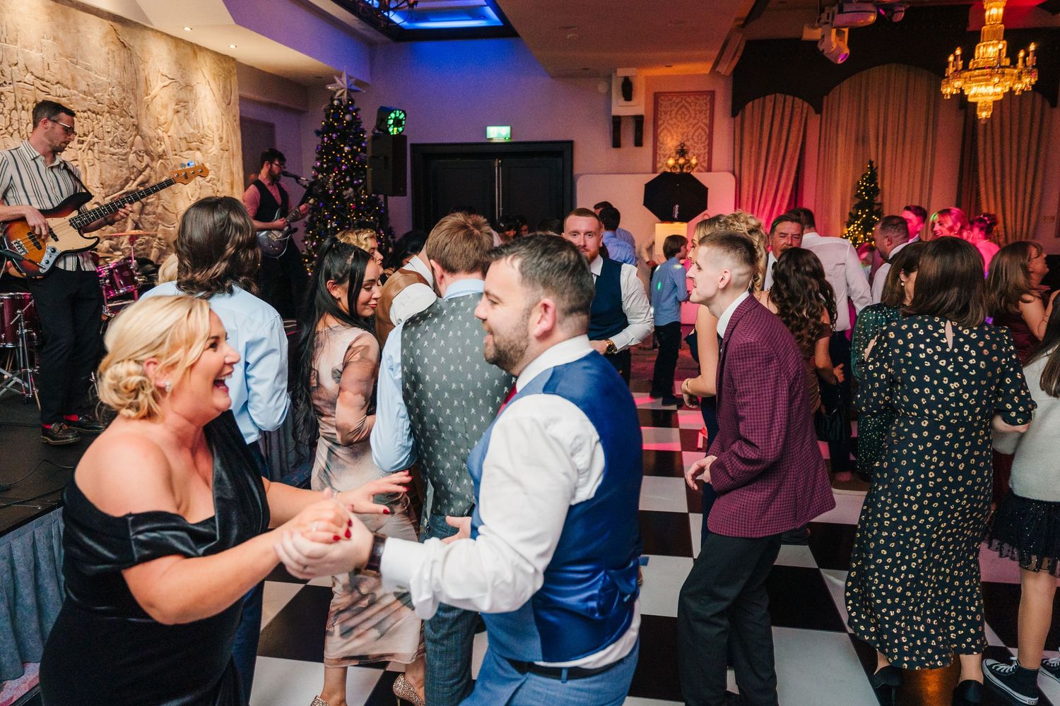 Lively dance floor scene with wedding guests enjoying themselves under colored lighting.City Hall Dublin Photographer