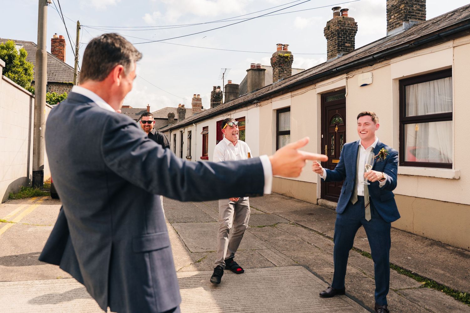 Wedding party members playfully posing on residential street during photo session. Same sex wedding PHOTOGRAPHER Dublin