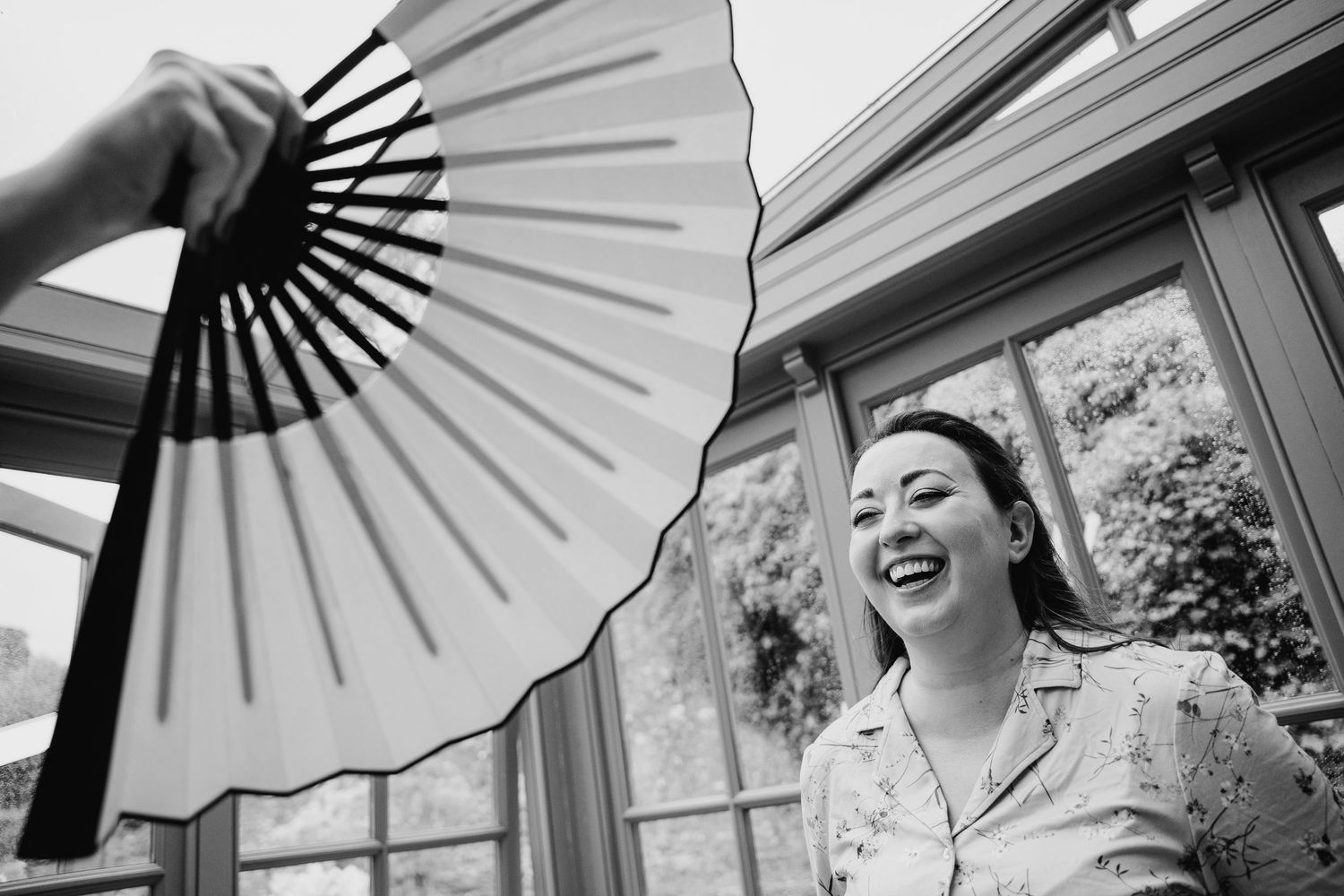 A person holds a decorative white and black folding fan while standing near a window. Wedding photographer Dublin