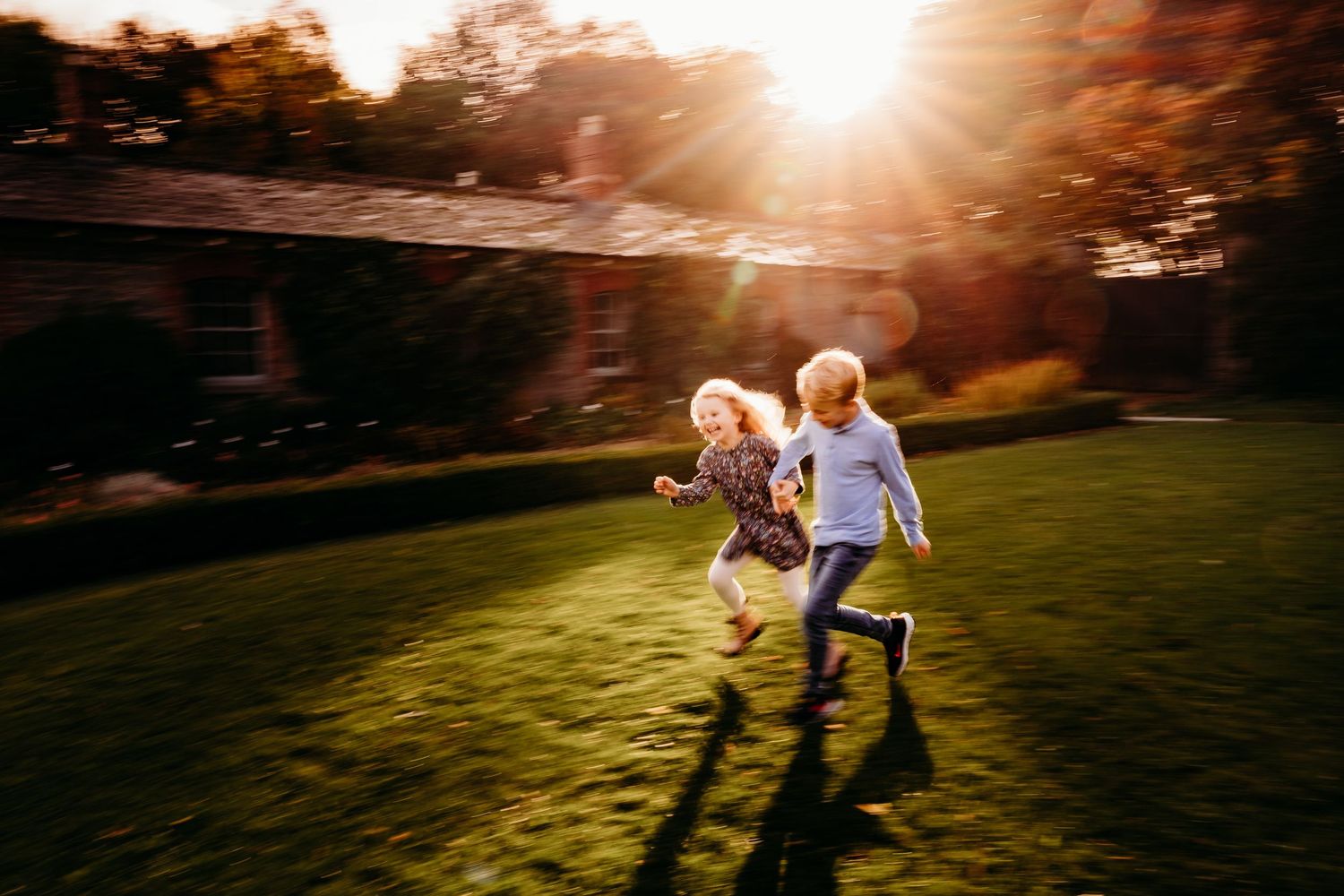 Children run and play together on a grassy hill at sunset creating silhouettes against the golden sky. family PHOTOGRAPHER Dublin