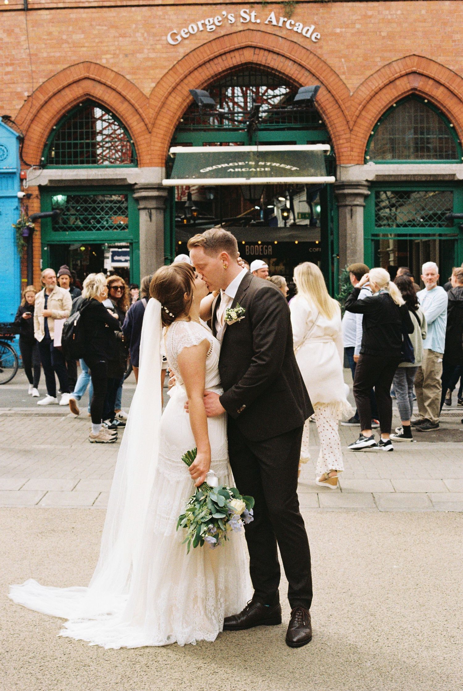 Wedding couple walking along the historic St. George's Arcade building in brick architecture with decorative arches.