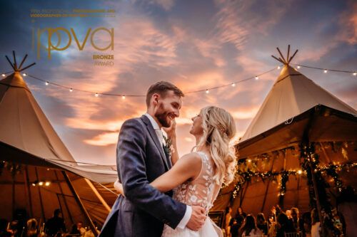 Wedding celebration under teepee tents at sunset with dramatic orange sky. Wedding PHOTOGRAPHER Dublin