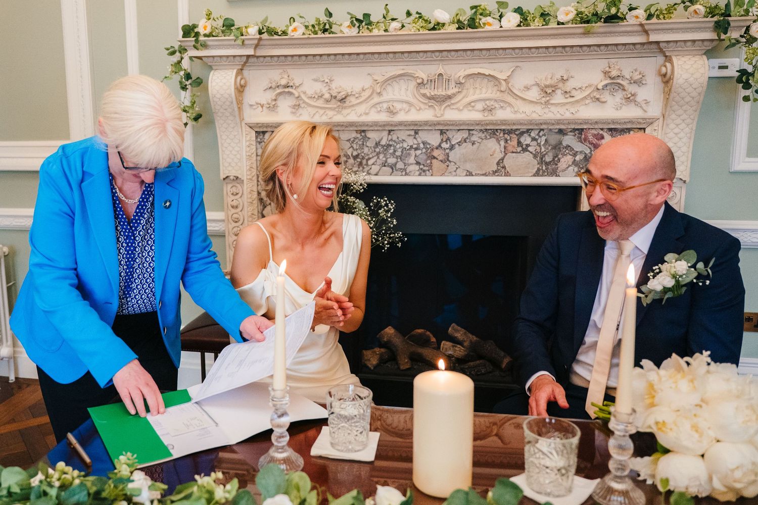 Group of people gathered around a table with candles and decorative greenery at an elegant dinner party. wedding photographer dublin pricing