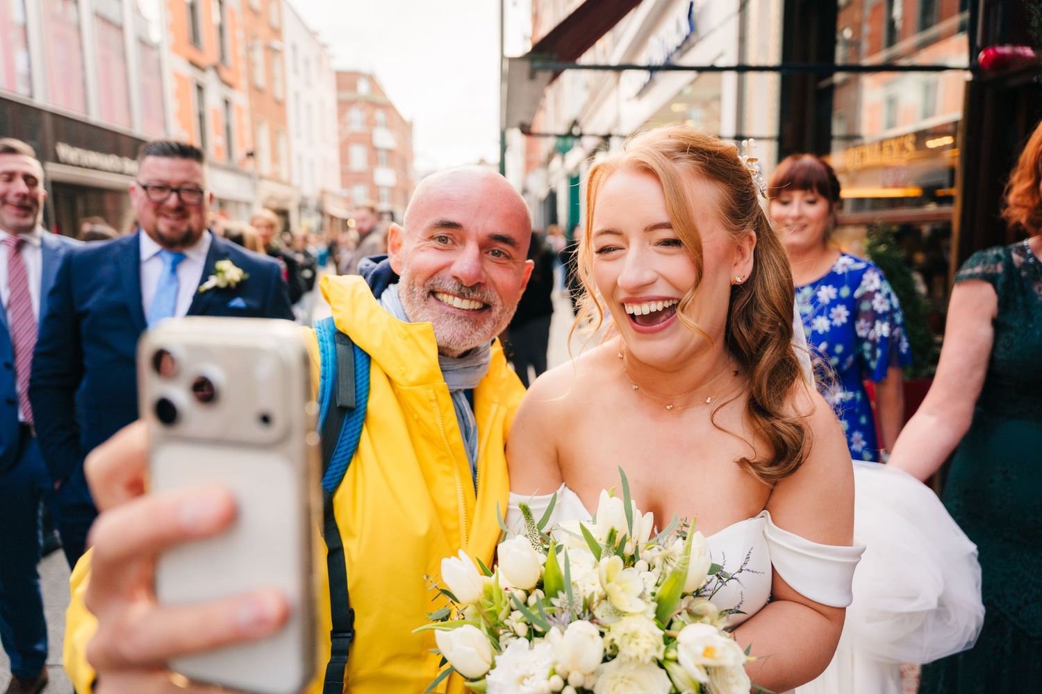Wedding party and guests gathered on a brick-lined street for outdoor photos. Dublin wedding photogrAPher Bewleys Grafton