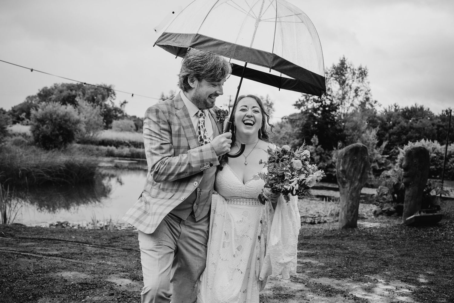 Black and white photo of couple walking through natural landscape with string lights overhead. Wedding photographer Dublin
