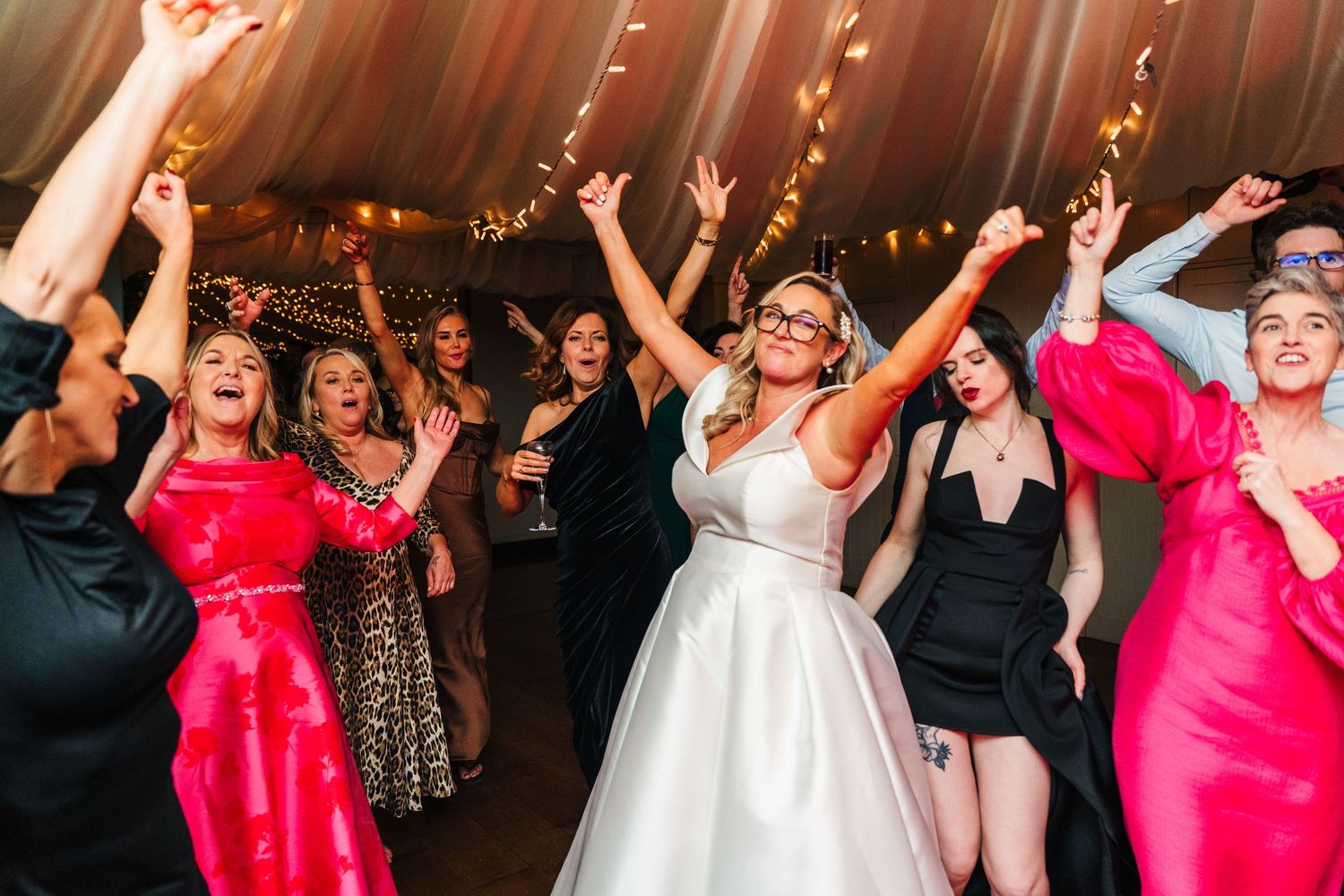 Wedding party dances enthusiastically on the reception dance floor under warm lighting.  Virginia Park Lodge Wedding Photographer Cavan Dubl