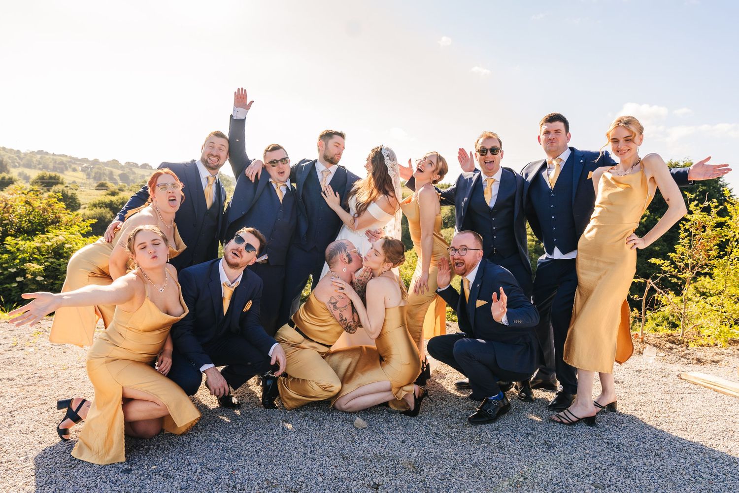 Poulaphouca Wedding photographer wicklow  Wedding party poses together outdoors in sunny setting wearing yellow and navy blue attire.