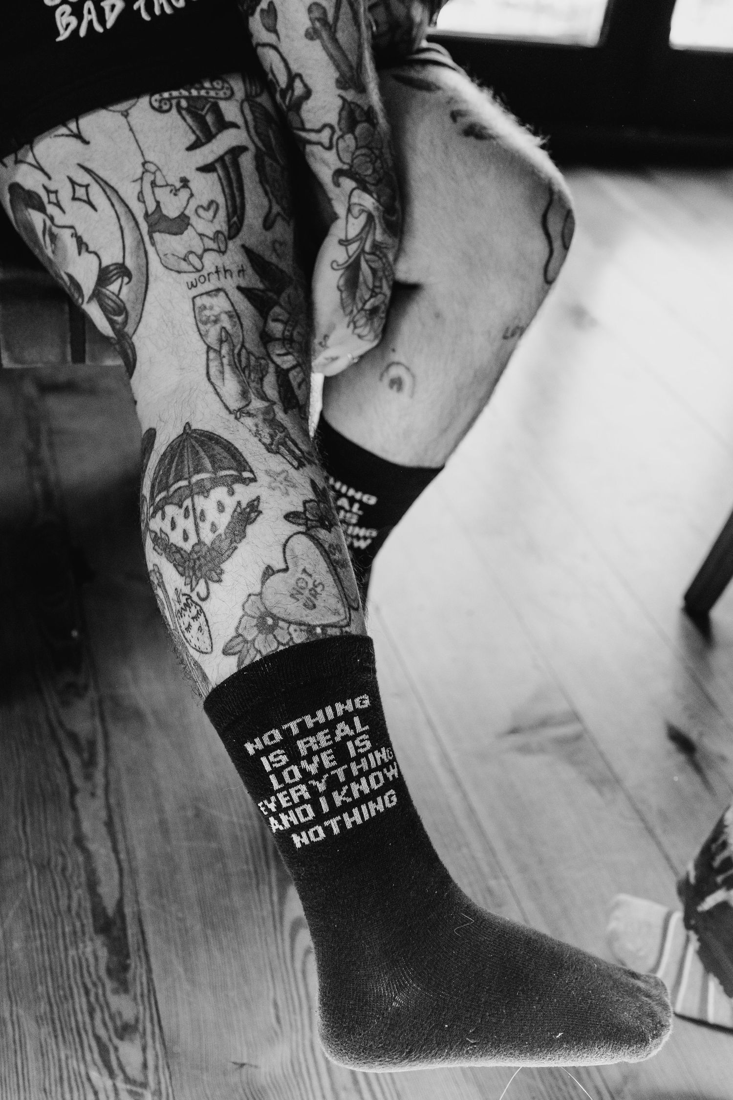 Poulaphouca Wedding photographer wicklow  Black and white photo of tattoo covered arm and leg with a text tattoo visible on sock.
