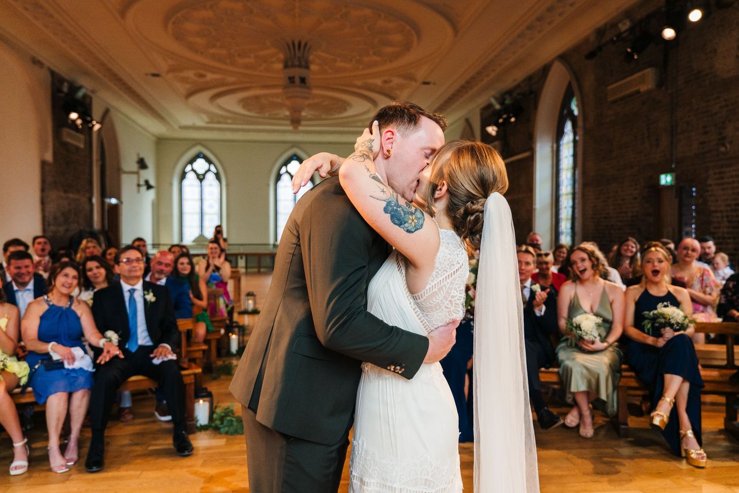 Wedding guests clap and cheer during a celebration in an ornate ballroom setting. PHOTOGRAPHER Dublin Ireland Wedding