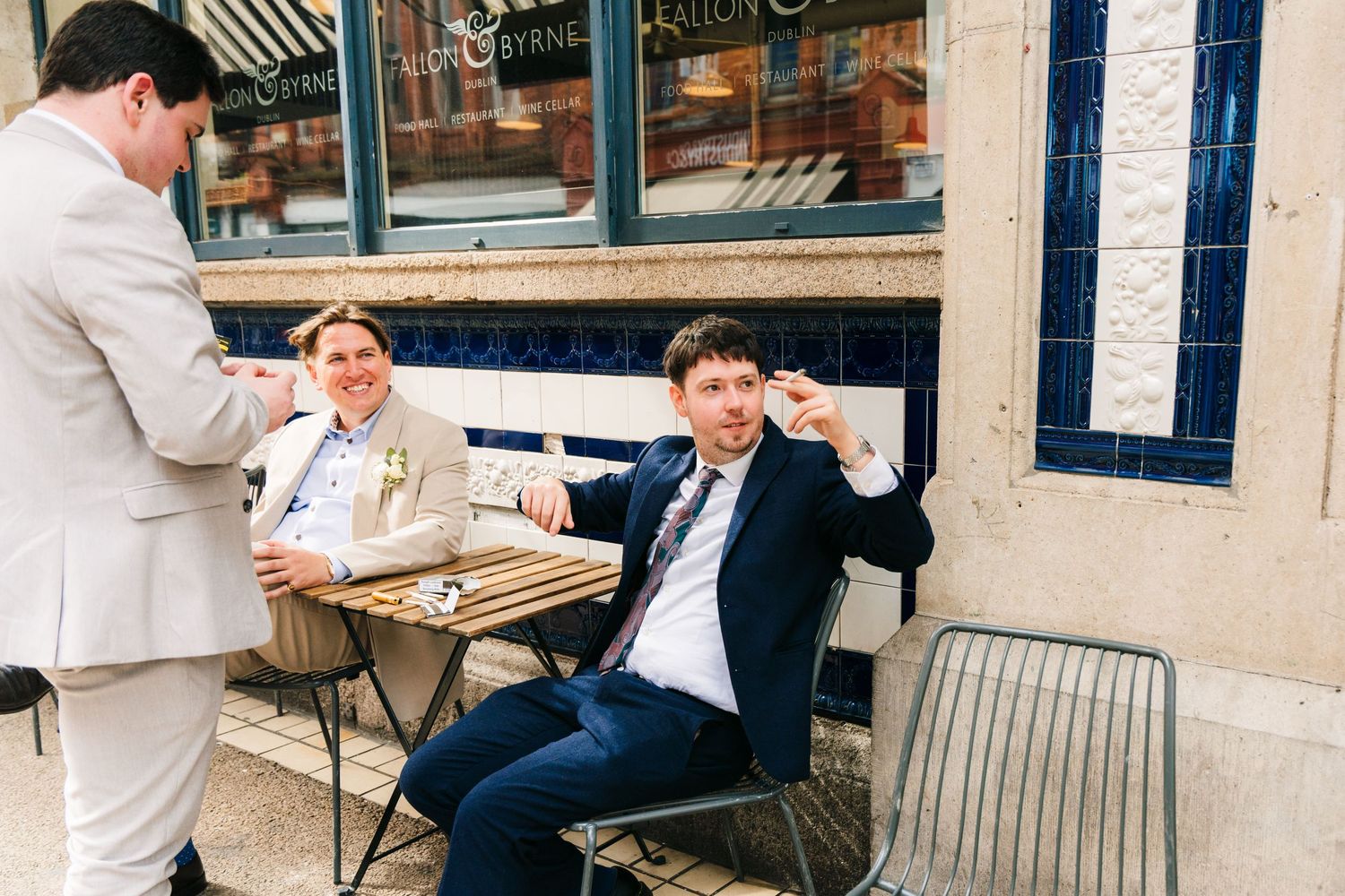 Wedding guests enjoying drinks at outdoor cafe table in casual celebration setting. PHOTOGRAPHER Dublin Ireland Wedding