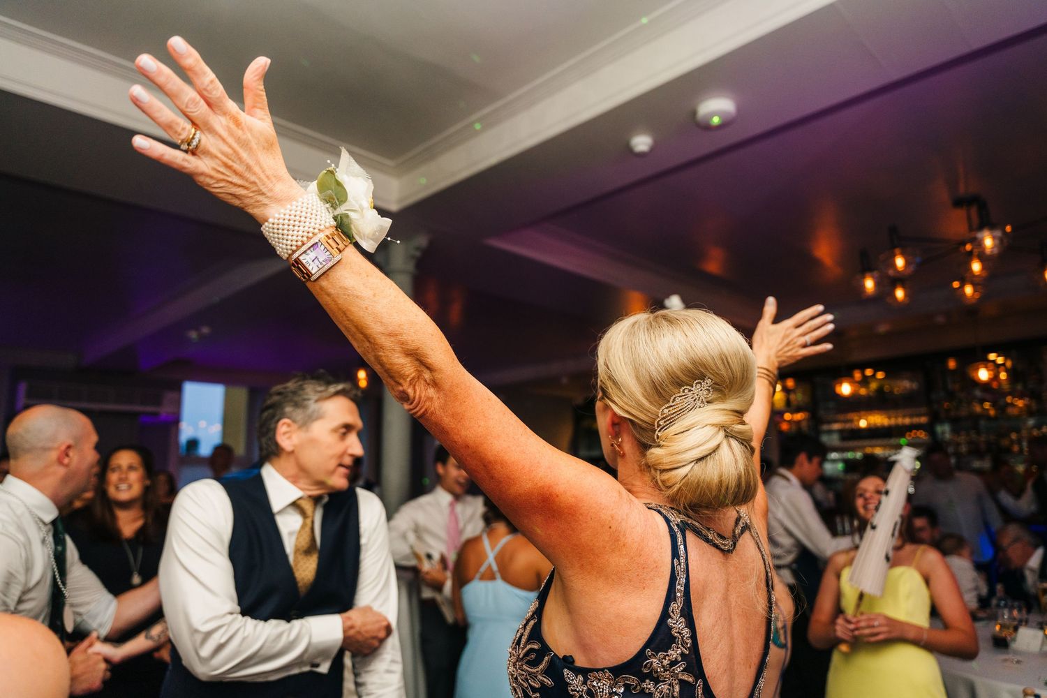 A wedding guest with arms raised dances enthusiastically during the reception party. PHOTOGRAPHER Dublin Ireland Wedding