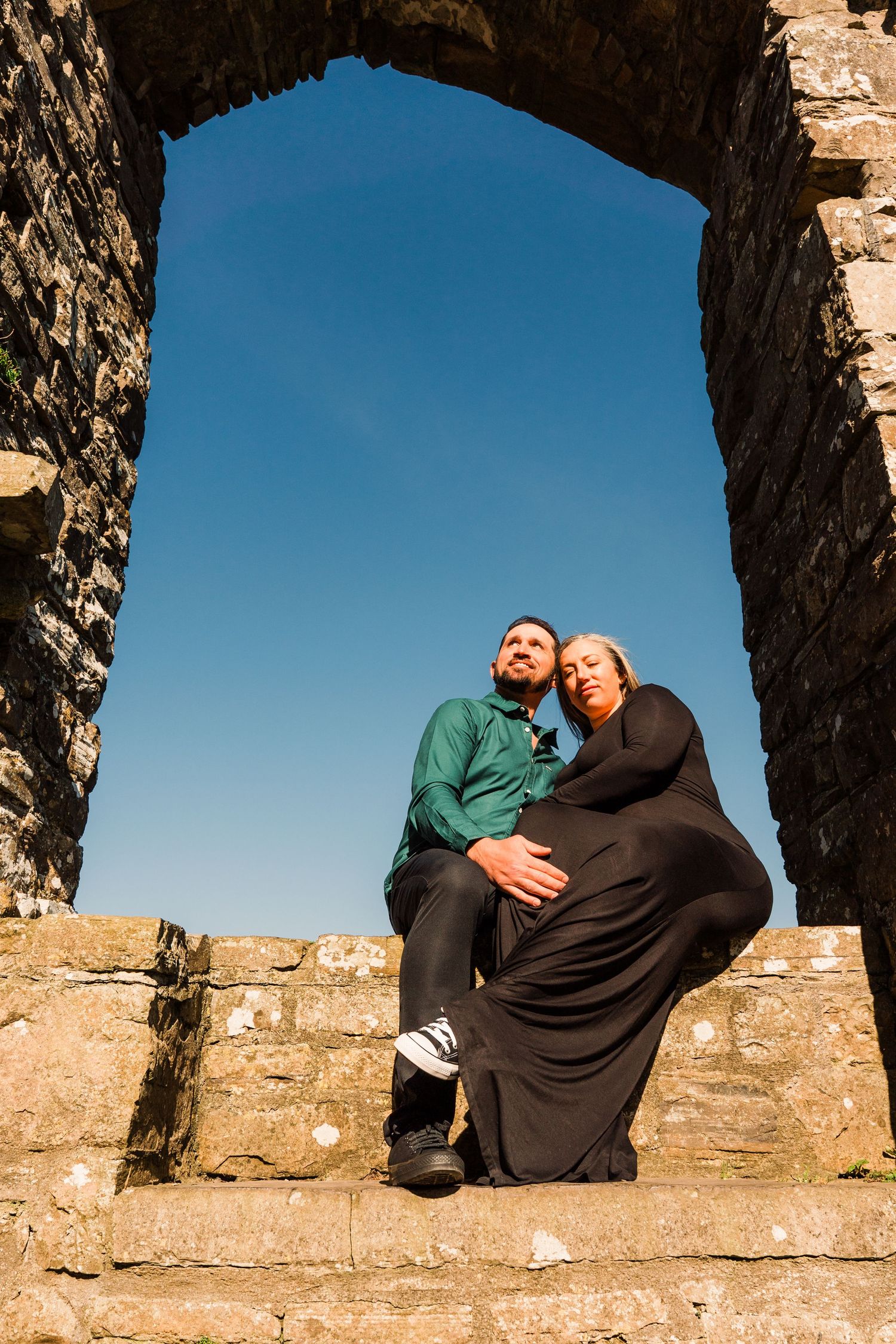 Series of arched stone windows at an ancient castle showing dramatic silhouettes against bright blue sky. Family PHOTOGRAPHER Dublin