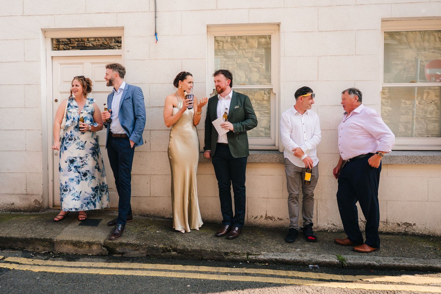 Wedding party posing casually against white walls of a building. Same sex wedding PHOTOGRAPHER Dublin