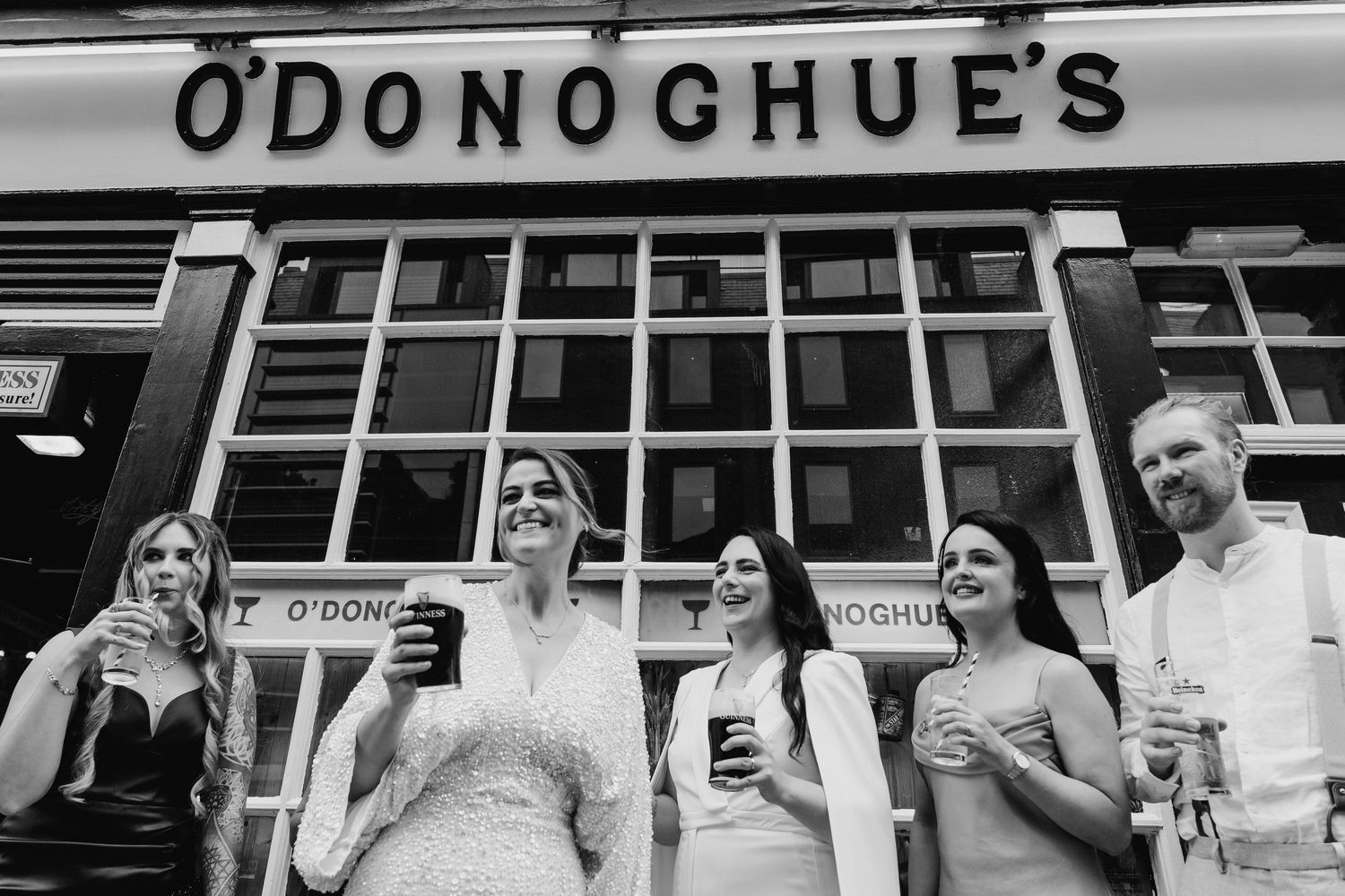 Wedding party posing outside O'Donoghue's pub storefront in casual poses. House Dublin Wedding Photographer