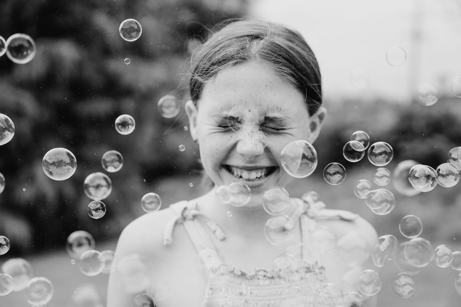 Black and white portrait surrounded by floating soap bubbles displaying pure joy and laughter. family PHOTOGRAPHER Dublin