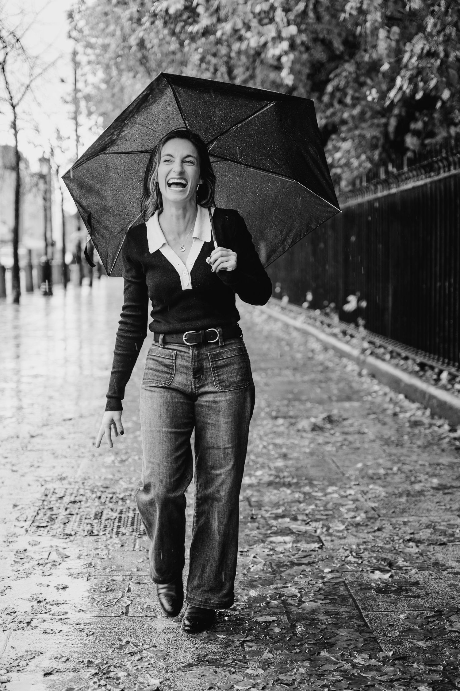 A sequence of black and white photos showing someone holding an umbrella walking through fallen autumn leaves on a path. professional headsh
