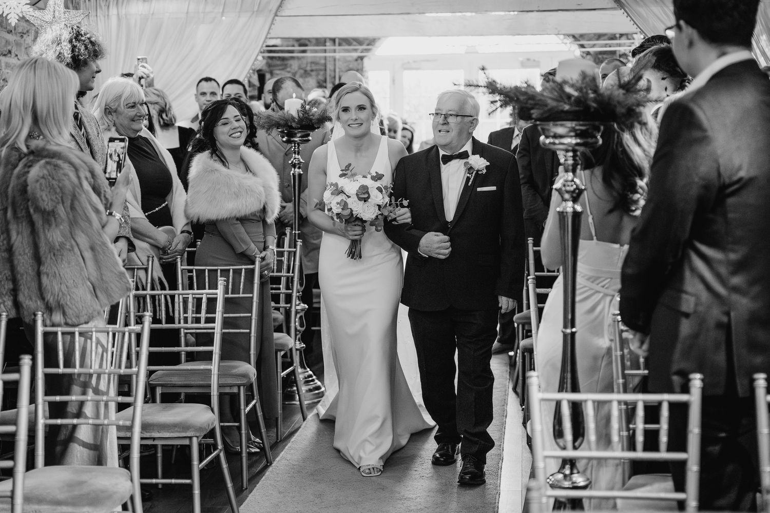 Wedding guests gathered at an elegant outdoor ceremony with white chairs. Ballymagarvey Wedding photographer