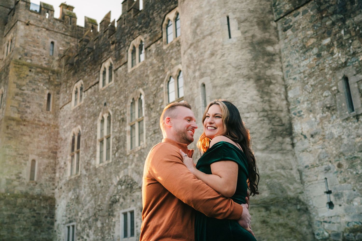 A couple shares romantic moments against a stone castle wall backdrop in a series of candid photographs.