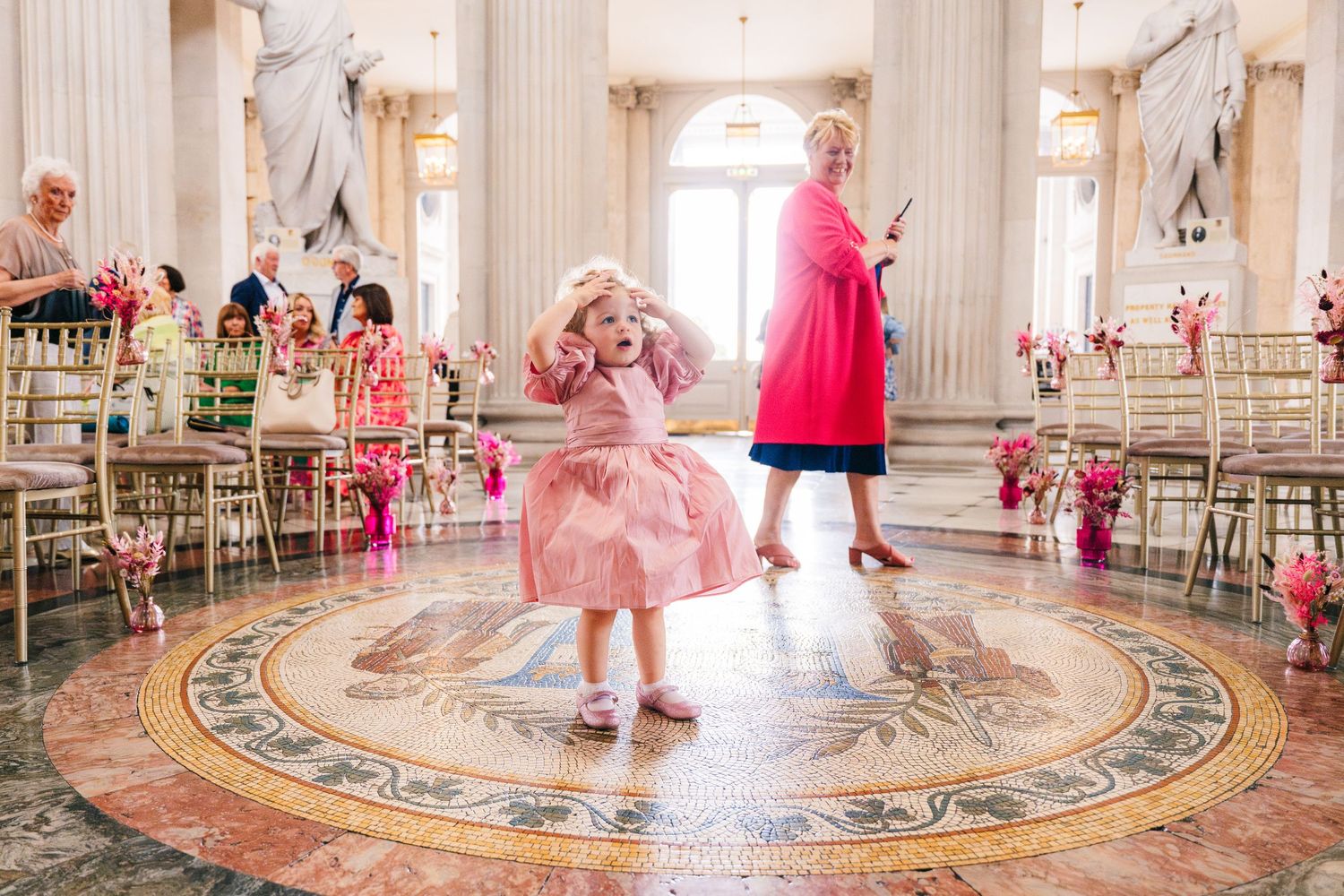 Dancers in pink outfits perform on an ornate marble floor with classical columns in the background.  city hall dublin wedding photos