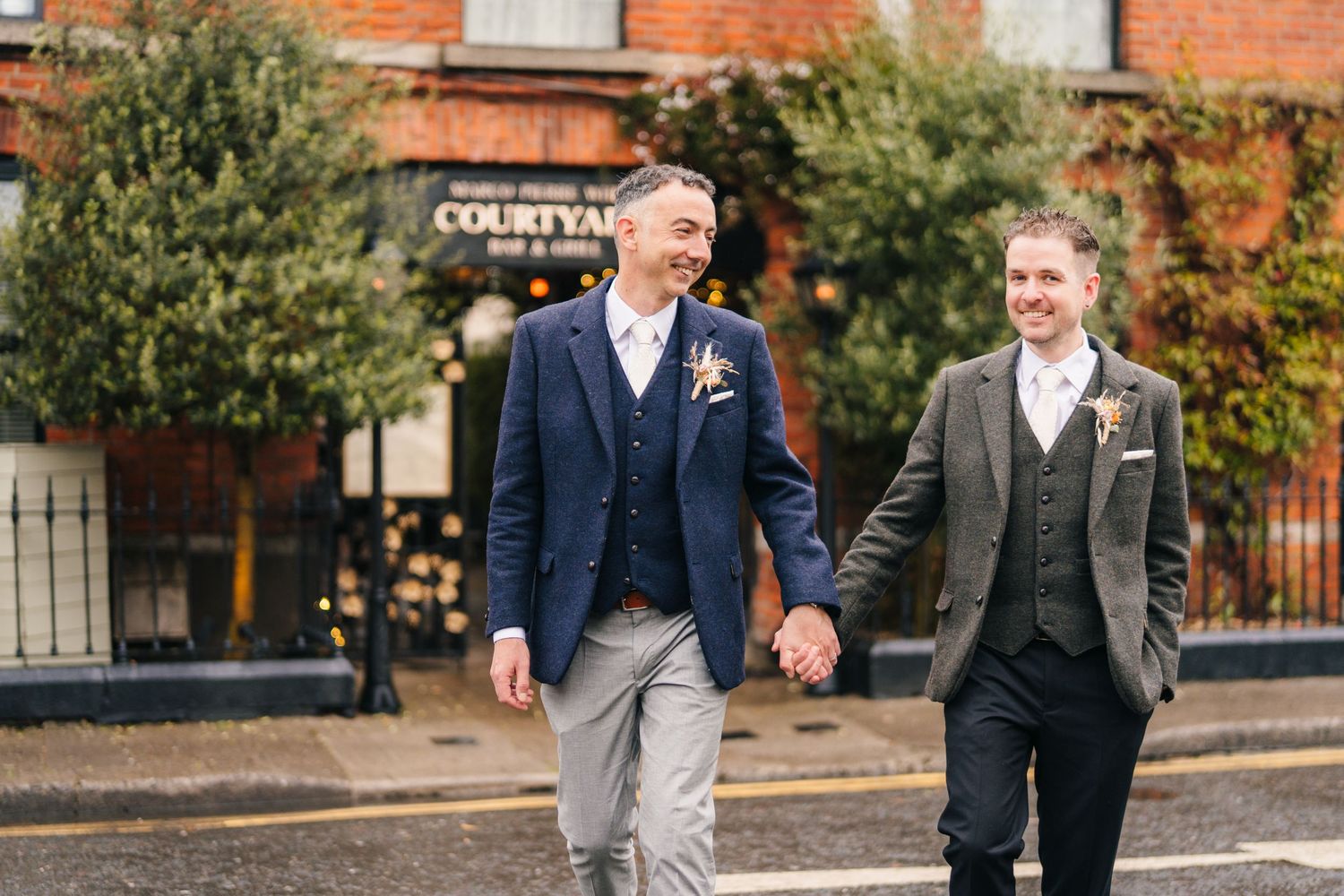 Guests in formal attire walking and chatting outside a brick building at a wedding venue. Marco Pierre Dublin Wedding Photographer