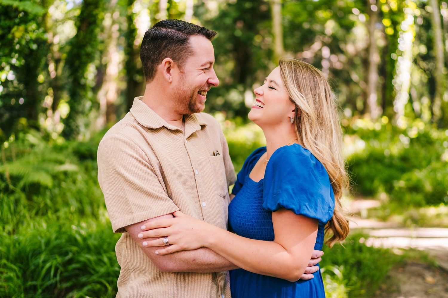 A couple in blue and khaki outfits shares loving moments together in a sunlit wooded park setting. PHOTOGRAPHER Dublin ireland
