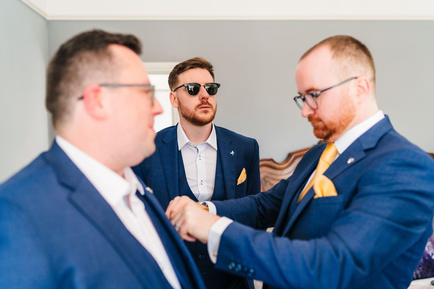 Poulaphouca Wedding photographer wicklow  Groomsmen helping adjust pocket square and boutonniere before wedding ceremony.