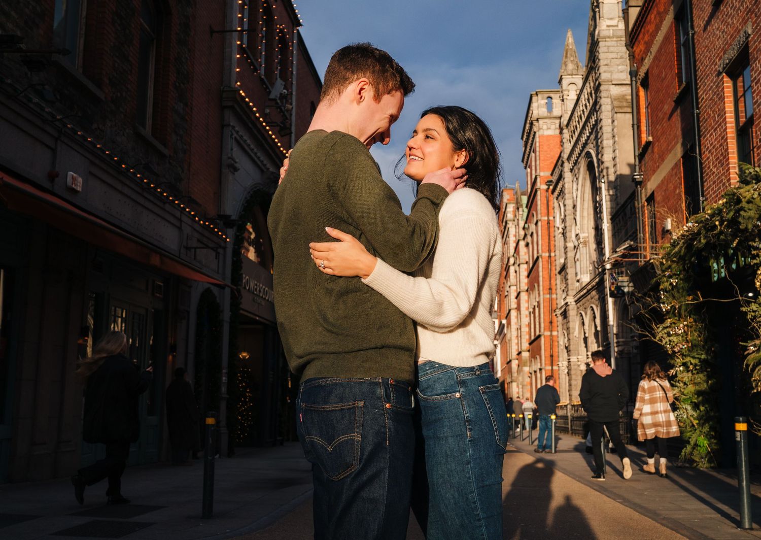 A couple sharing an intimate moment while standing on a charming brick-lined street in a historic city district. Surprise proposal dublin ph