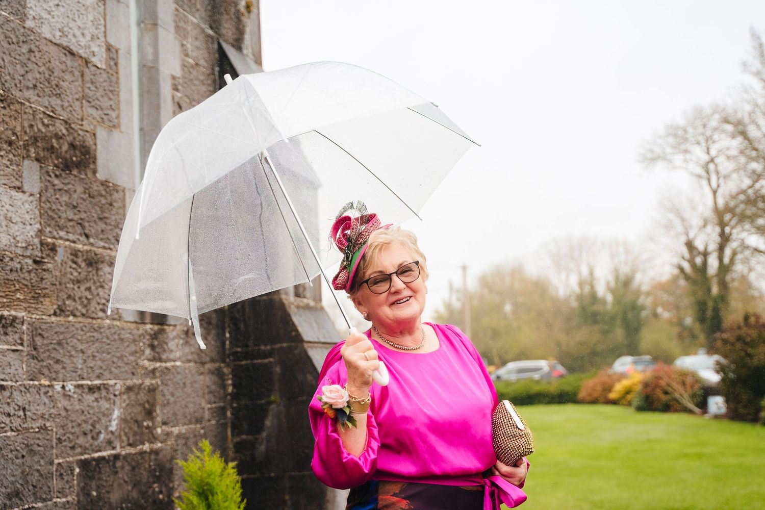 Outdoor wedding photos with umbrellas against stone church architecture.