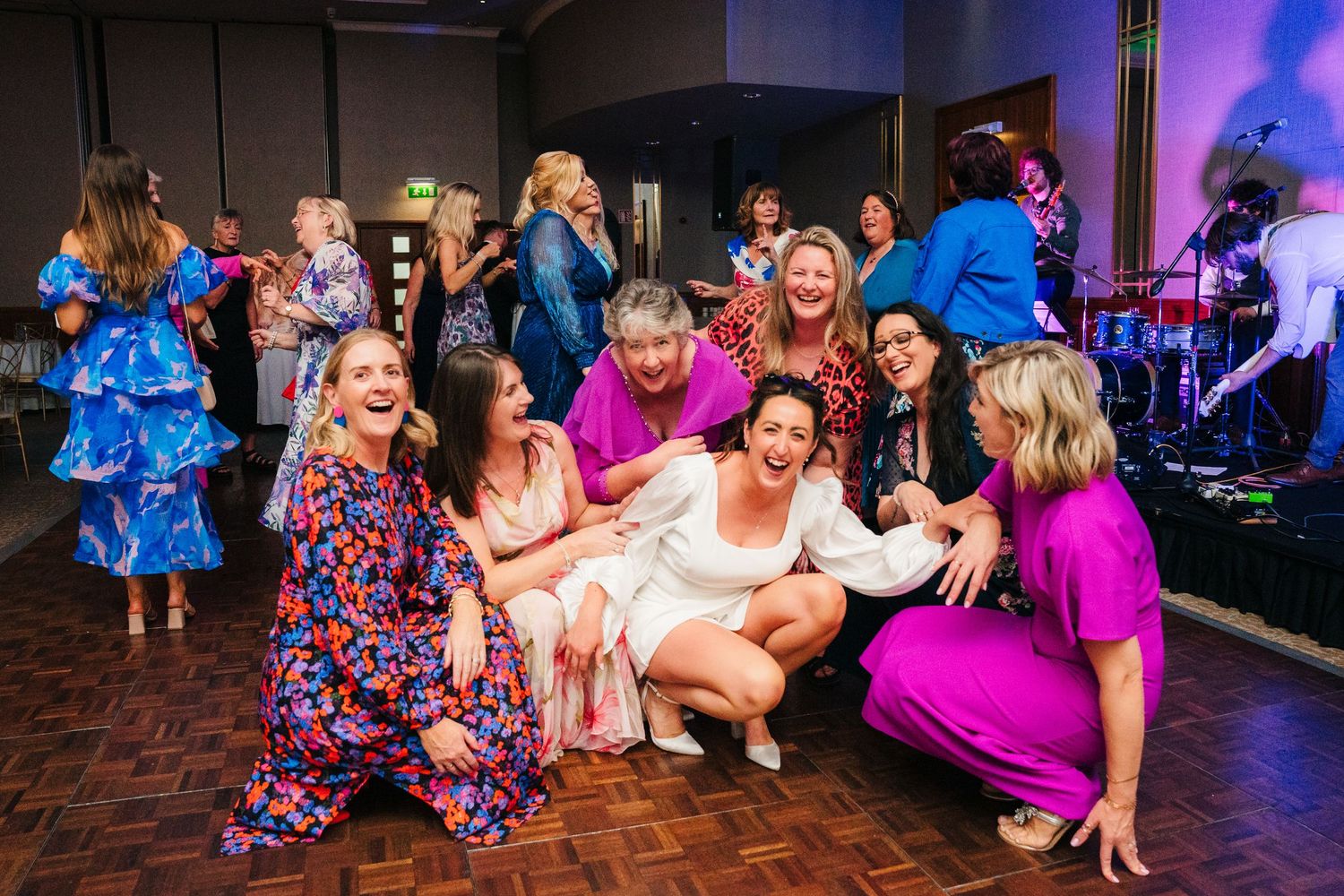 Group of wedding guests in colorful dresses celebrating on dance floor with live band.Wedding Photography Trim Castle Ireland