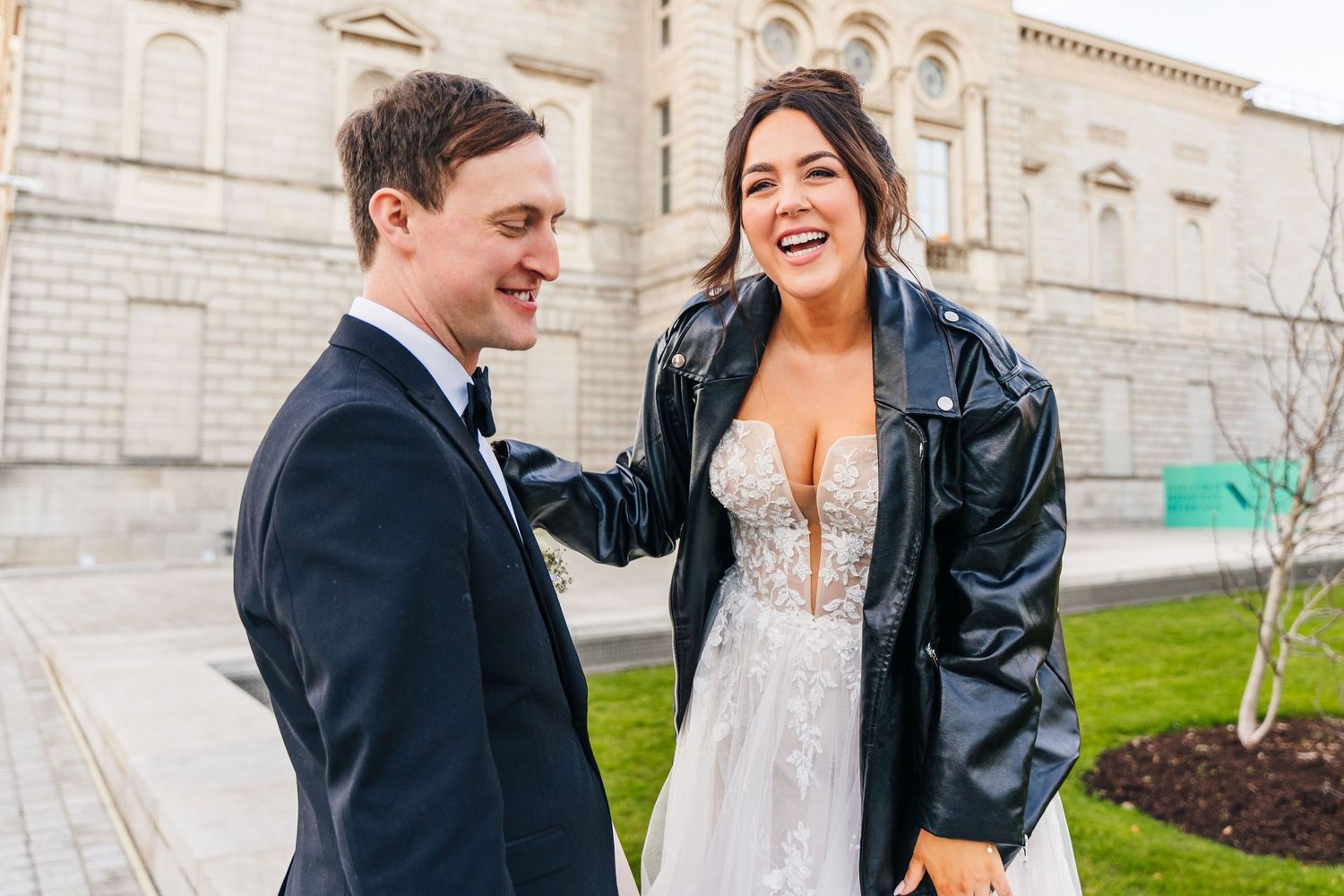 A happy couple shares a candid moment outside a historic stone building during their wedding. Wedding PHOTOGRAPHER Dublin