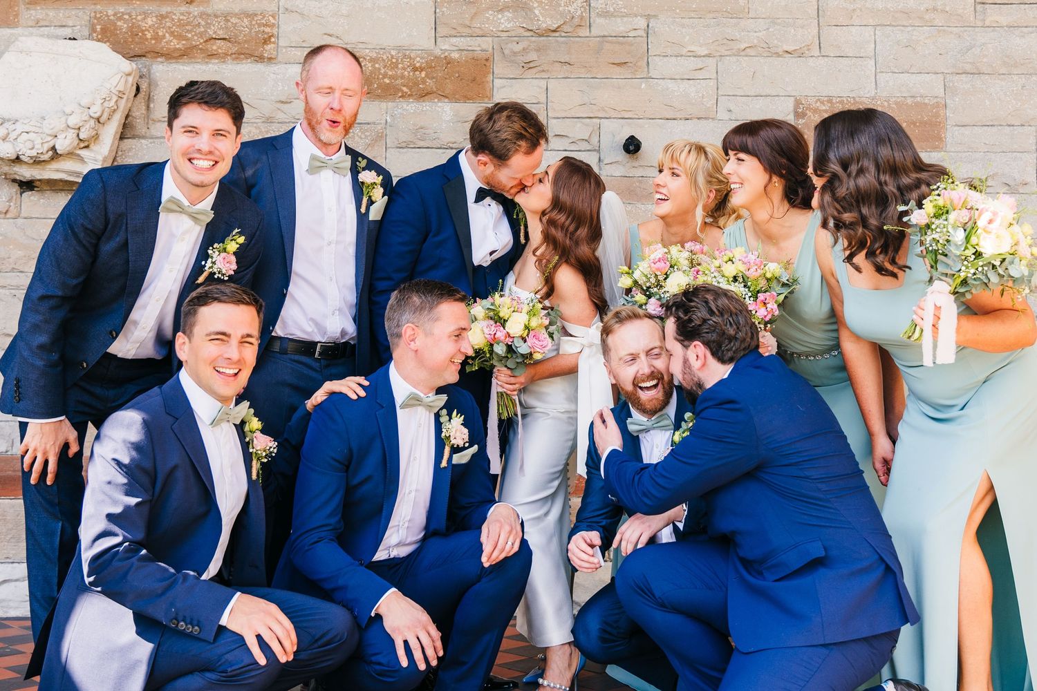 Castle Leslie Wedding Photographer Dublin Wedding party in blue suits and pastel dresses pose together for a casual outdoor group photo.