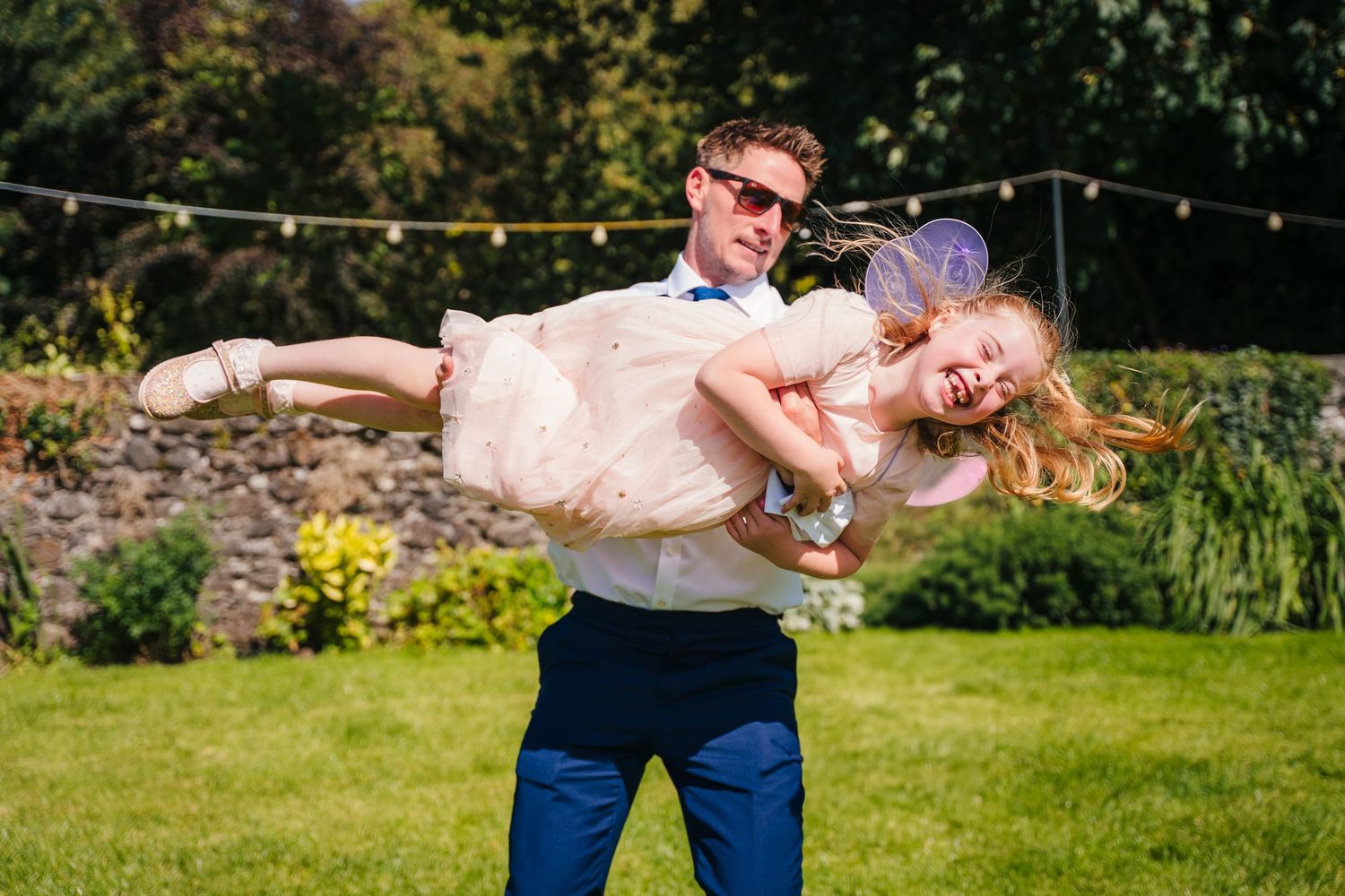 A playful moment captured in a garden as a couple dips dramatically on the lawn. . Village Barn Tyrrellspass wedding photographer Ireland