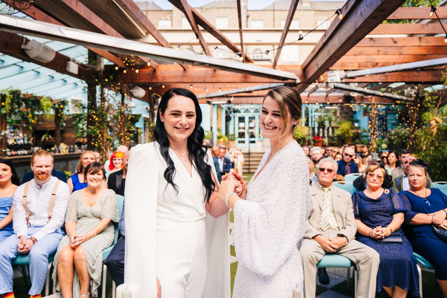Wedding celebration under covered patio with guests mingling and seated in rows. House Dublin Wedding Photographer