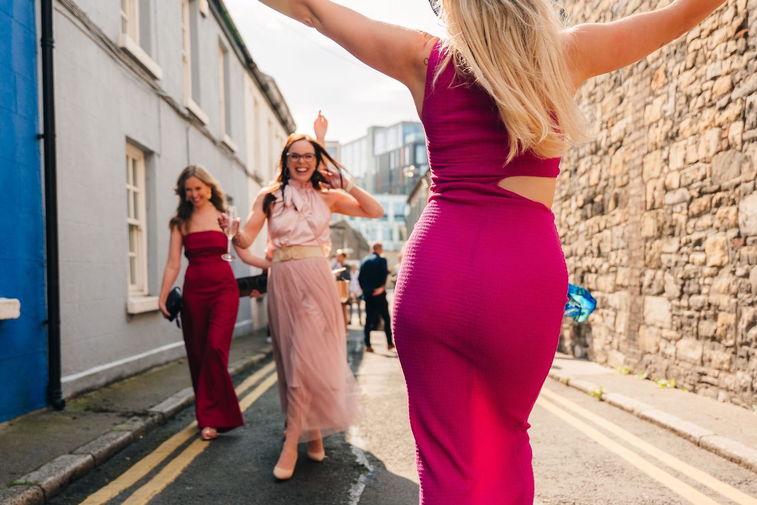 Women in formal dresses dancing and celebrating in the street. Same sex wedding PHOTOGRAPHER Dublin