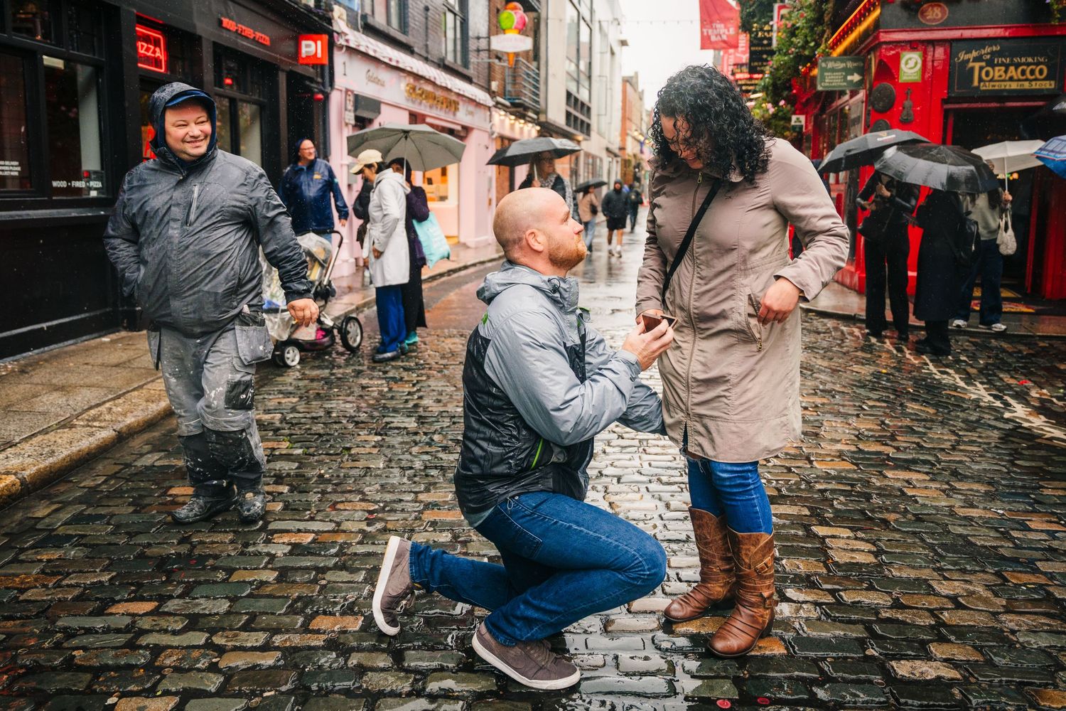 A series of photos on a cobblestone street during a proposal where one person kneels to propose to another. Proposal Dublin Photographer