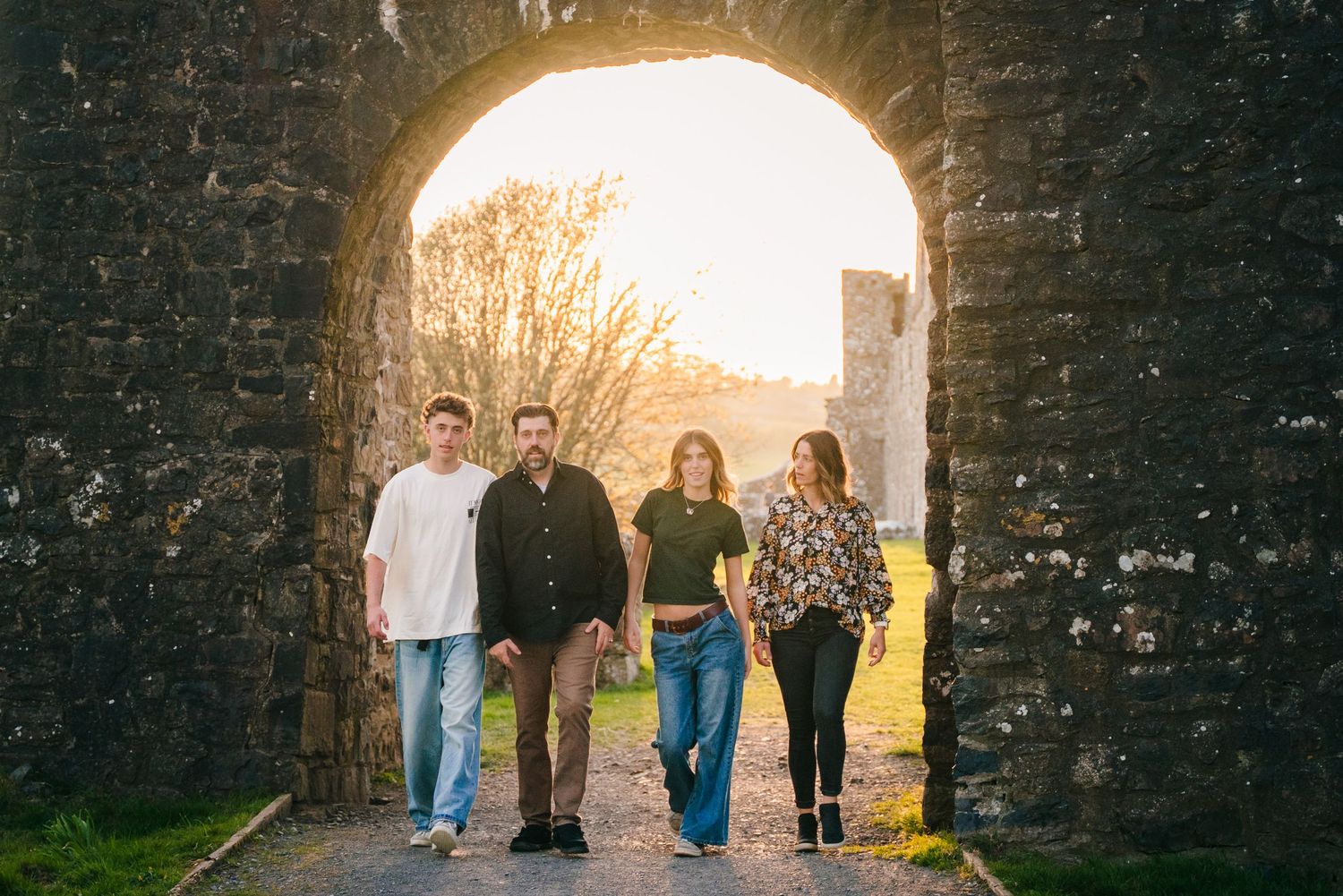 Silhouetted figures standing in ancient castle archway during golden sunset light. Photographer Ireland dublin