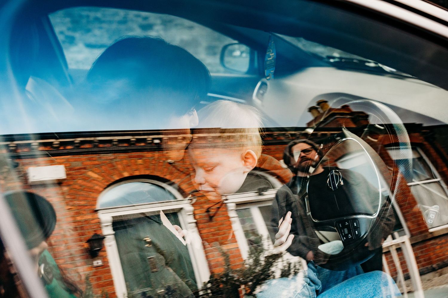 View through a car window showing reflections and urban architecture in the background.  Family PHOTOGRAPHER Dublin