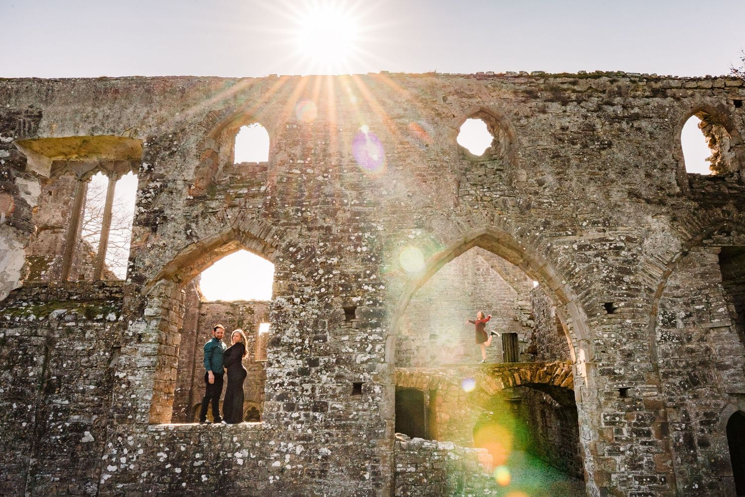 Ancient stone ruins with arched windows and dramatic sunlight streaming through. Family PHOTOGRAPHER Dublin