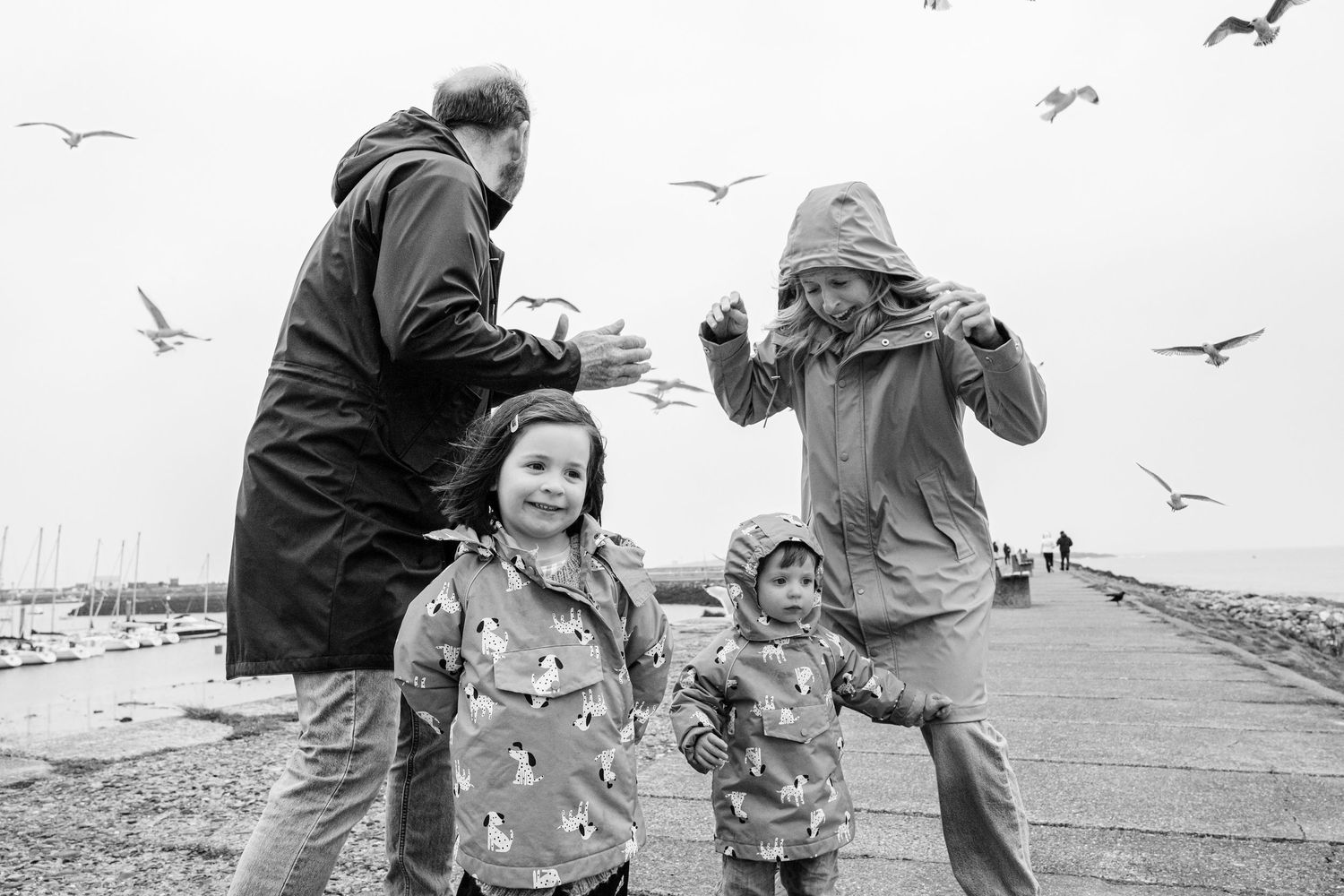A family enjoys feeding seagulls on a pier together on an overcast day. PHOTOGRAPHER Dublin