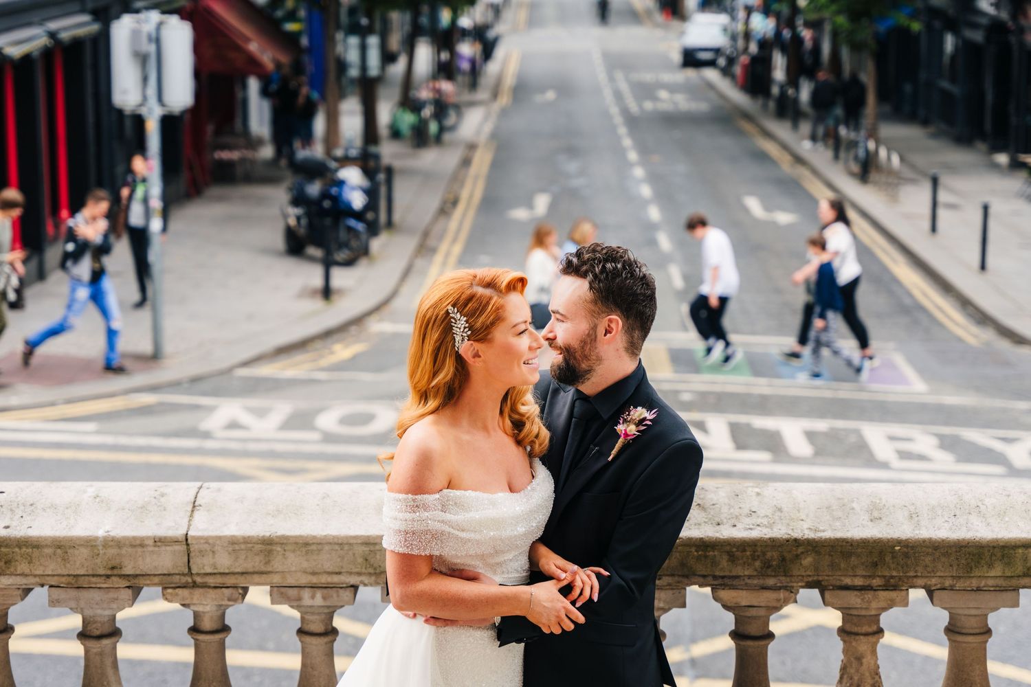 Wedding couple embracing on stone balcony overlooking city street.  city hall dublin wedding photos
