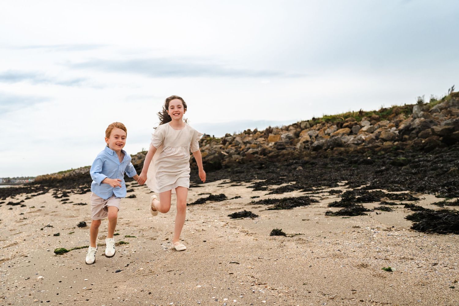 Playful group walking and running along a scenic beach shoreline. Family photographer Dublin Ireland