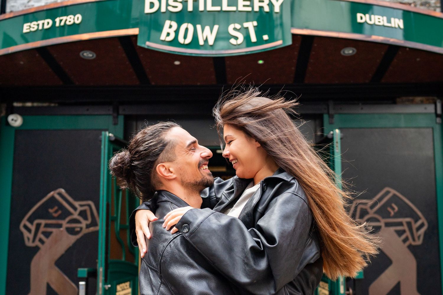 The storefront of an Irish distillery in Dublin with traditional green exterior and signage lit up at night. Couple's Photoshoot PHOTOGRAPHE