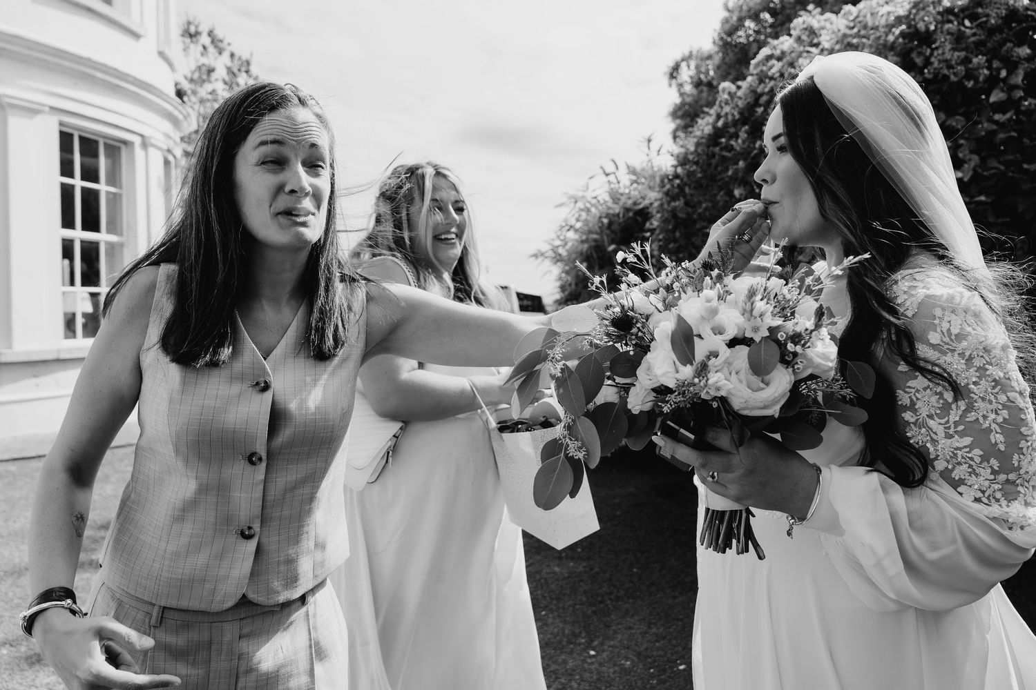 Black and white candid moment of wedding party members with bouquets outdoors. Wedding photographer dublin