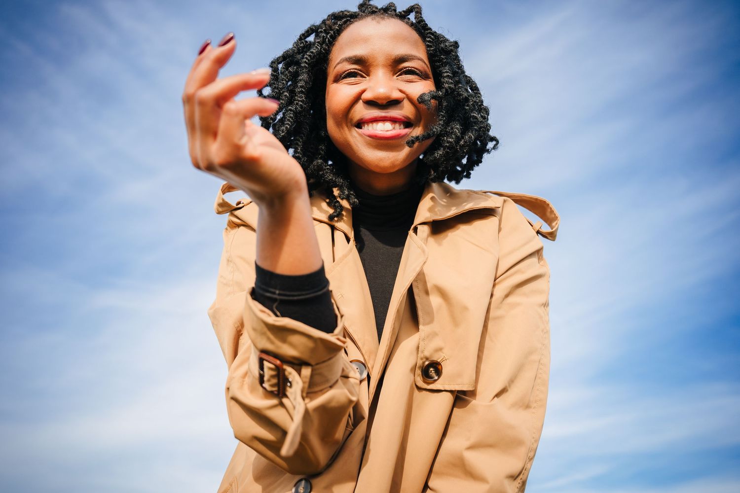 Person in tan coat expresses joy against bright blue sky. Dublin professional headshots photographer