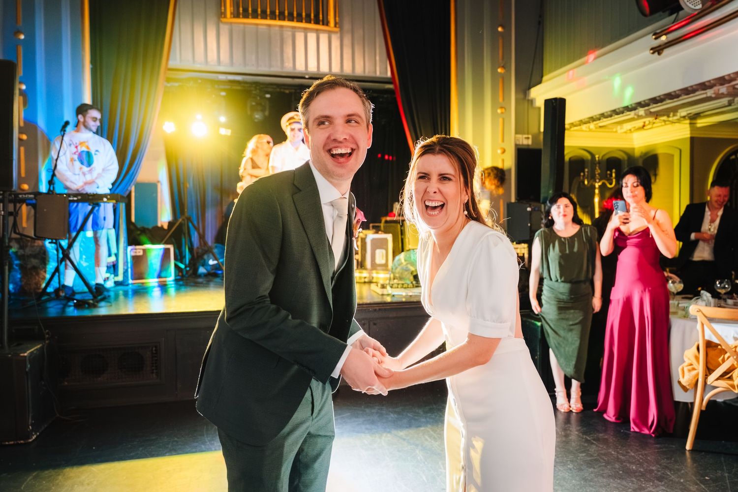 Couple dancing at their wedding reception with stage lights and decorative venue backdrop. Wedding ceremony at the Set Theatre Langtons Hote