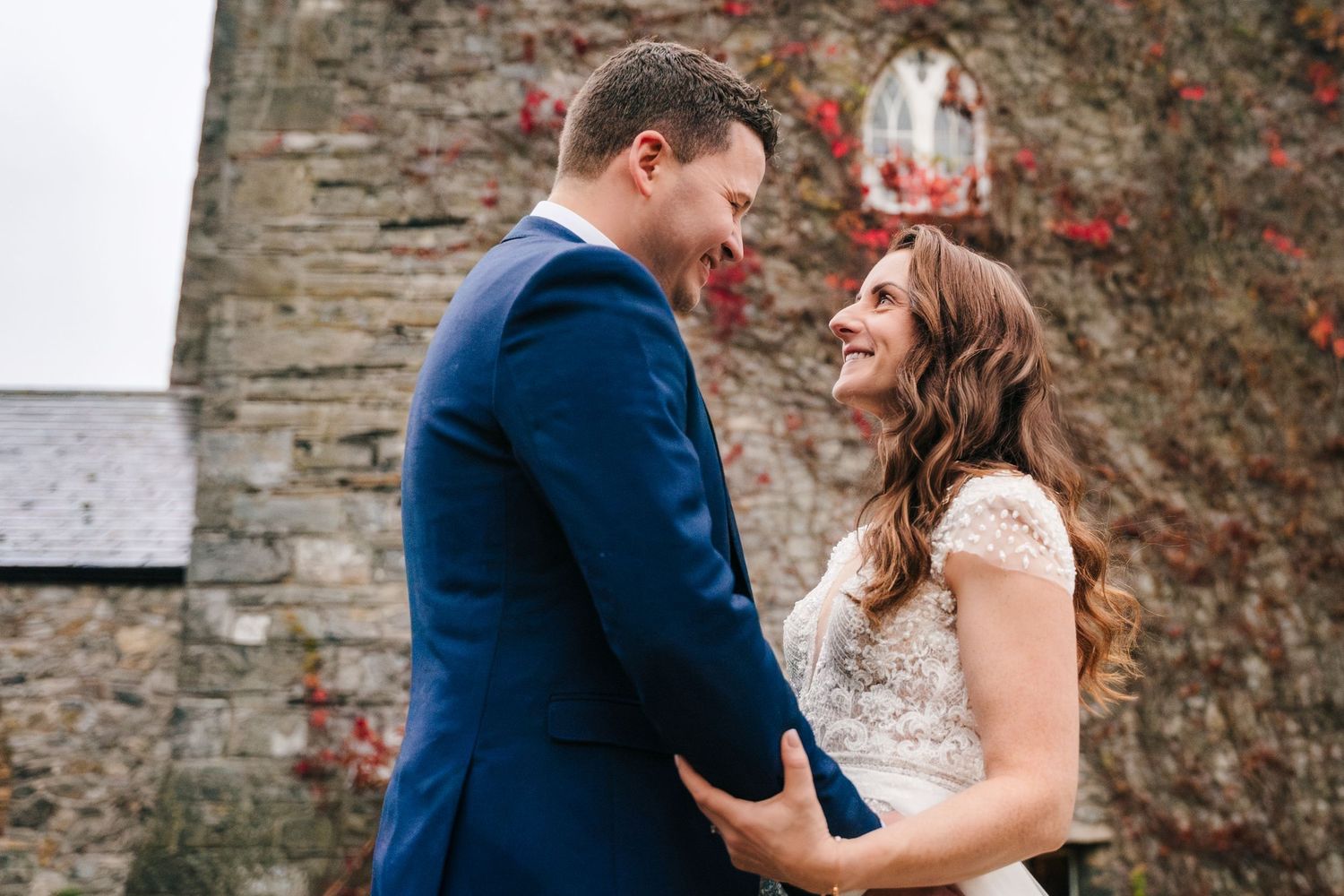 Romantic wedding portraits against rustic stone wall backdrop.