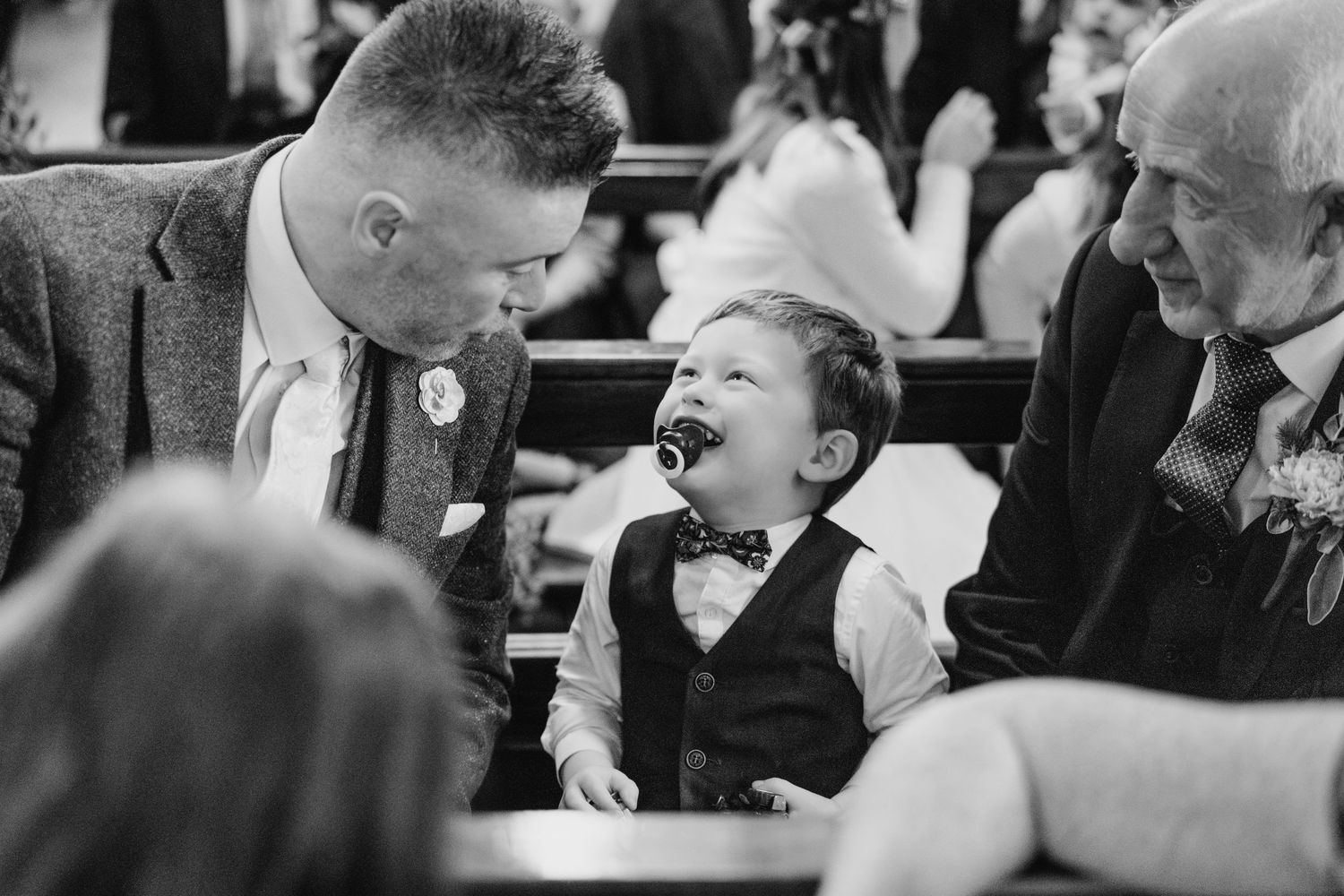A black and white photo showing people laughing and smiling at a social gathering.